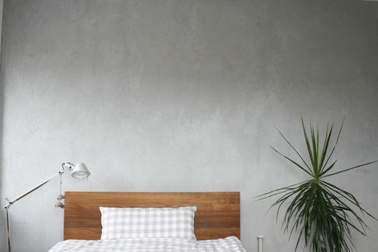 Ein Bett steht vor einer Wand in Betonoptik