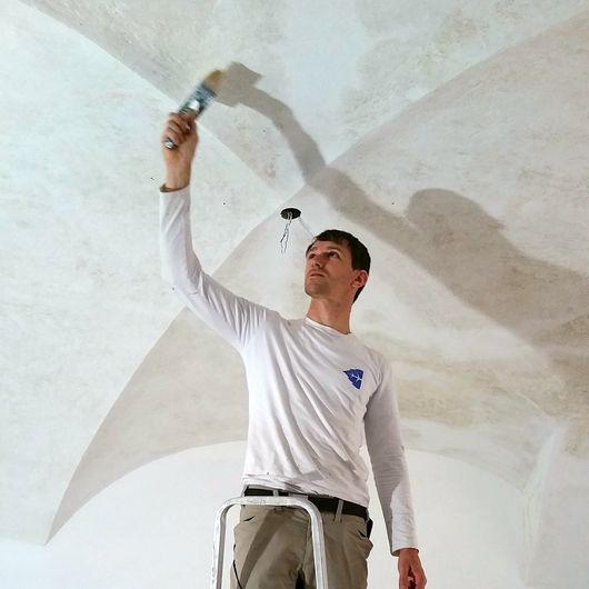 Marold Niedersteiner streicht eine Kreuzgewölbe-Decke