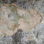 Abplatzung der Zementputzschicht. Barocke Fassung ist sichtbar