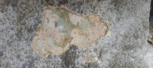 Abplatzung der Zementputzschicht. Barocke Fassung ist sichtbar