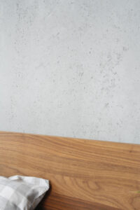 Wand in Betonoptik hinter Bett