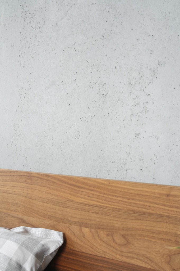 Wand in Betonoptik hinter Bett